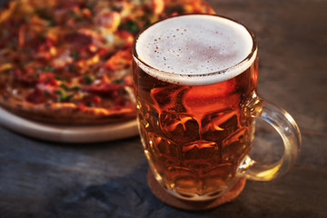 Delicious pizza  and glass of beer are on wooden table