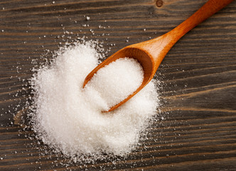 Spoon with sugar on a wooden table