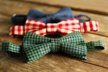 Different bow ties on wooden background