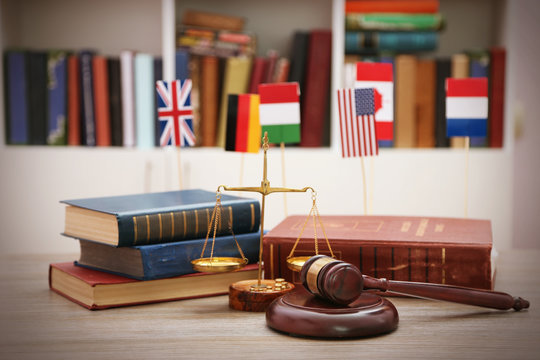 Gavel with justice scales and stack of books on wooden table