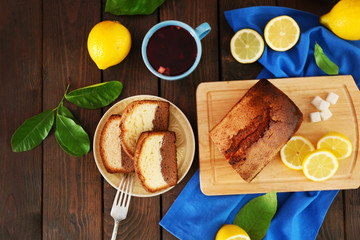 Delicious sweet cake bread with lemons on wooden table, top view