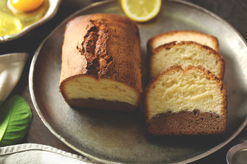 Delicious sweet cake bread in metal tray with lemons on wooden table closeup
