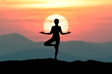 Silhouette Yoga woman meditating on the beach during Omega sunset (sunset blood colors) or Inferior-Mirage Sunset