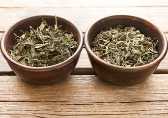 Two kinds of tea in a round bowls on wooden table, close up