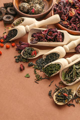 Different types of tea presented in the wooden scoops and spoons, close up