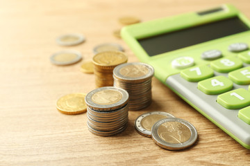Money concept. Green calculator with coins on wooden table