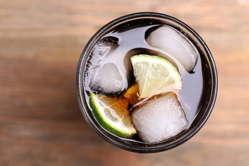 Cocktail with lime slices and ice blocks on wooden table, top view