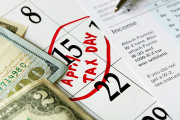 April tax day written and pinned in a calender with dollar bills, close up