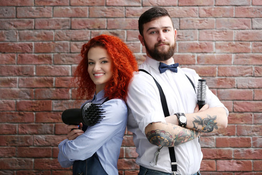 Two professional hairdresser on brick wall background