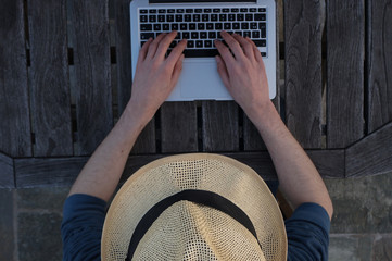 Homme, chapeau et ordinateur portable sur table en bois