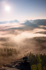 Fantastic dreamy sunrise above deep valley hidden the rocky mountains