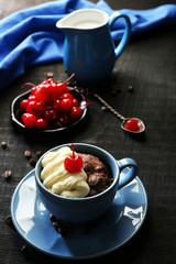 Chocolate cake in a blue mug with a cherry on a dark background, close up