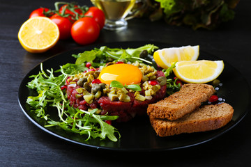Beef tartare served in a round plate with croutons, close up