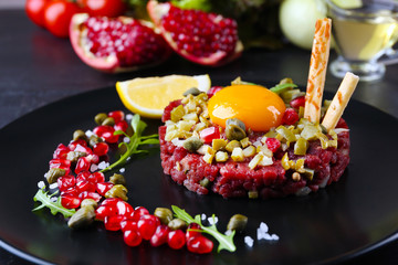 Beef tartare served in a round black plate, close up