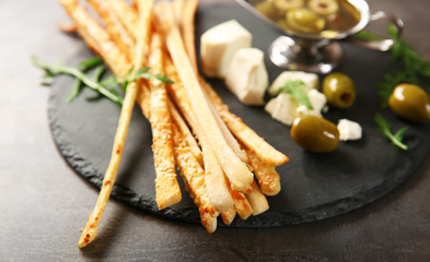 Bread sticks grissini with sesame seeds on a slate plate, close up