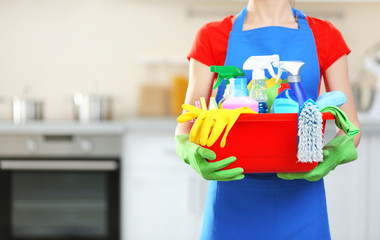 Cleaning concept. Young woman holds basin with washing fluids and rags in hands, close up