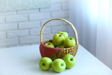 Ripe green apples in basket on a kitchen table