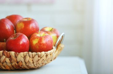 Ripe red apples in wicker basket on a kitchen table