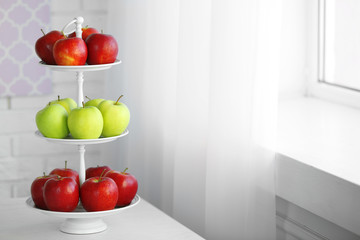 Ripe red and green apples on a stand in kitchen