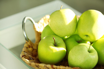 Ripe green apples in wicker basket, closeup