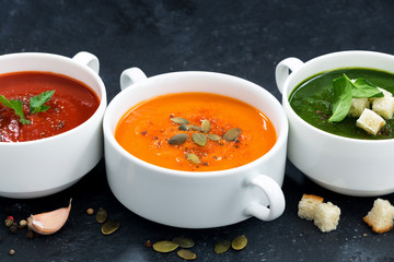 assortment of vegetable cream soup on a dark background, closeup
