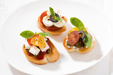 bruschettas with tomatoes and mozzarella on plate, top view