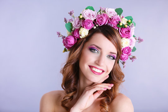 Beautiful young woman wearing floral headband on a grey background