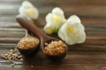 Wooden spoons with sea salt and exotic flower on wooden background