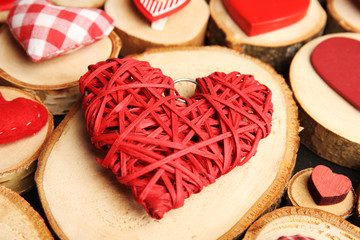 Red wicker heart on wooden log, close up