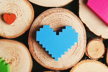 Plastic blue heart on wooden log, close up