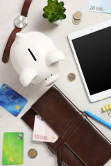 Piggy bank, office supplies and money on a white desk, top view