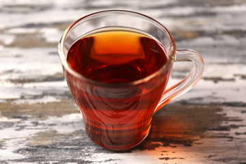 Glass cup of black tea on wooden table closeup