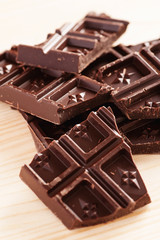 Dark chocolate broken into pieces on a wooden table