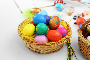 Fototapeta na wymiar Colorful Easter eggs in wicker baskets on table closeup