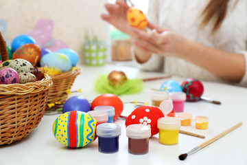 Female hands painting Easter egg at table indoors