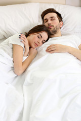 Young cute couple sleeping together in bed.