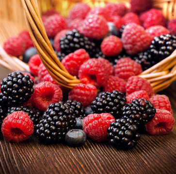 different berries in a basket on a wooden table