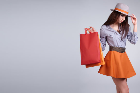 Woman holding shopping bags against a grey background