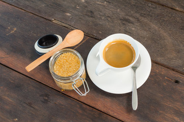 Brown sugar with wooden spoon and a cup of Espresso on wood table, selective focus