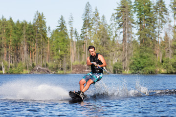 Young man riding wakeboard on a summer lake