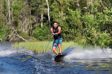 Young man riding wakeboard on a summer lake