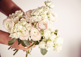 Beautiful bouquet of ranunculus and roses in man hands.