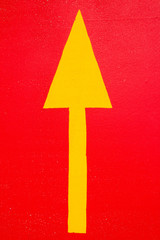 Fototapeta premium Yellow traffic arrow road sign on the red street asphalt background