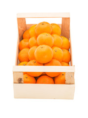 Ripe, juicy tangerines in a wooden box stacked as pyramid, on a white background