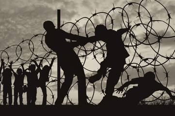 Silhouette of refugees and barbed wire