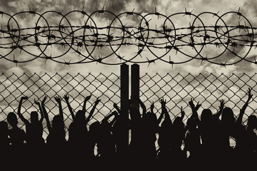 Silhouette of refugees and barbed wire