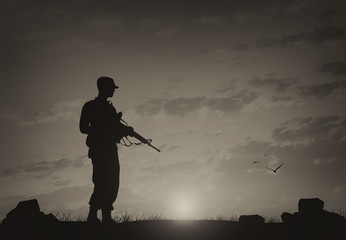 Silhouette of man with weapon against cloudy sky