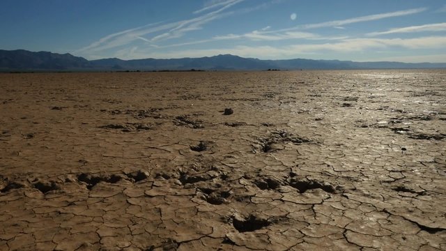 A dolly shot of dry cracked mud on a parched lake in the desert