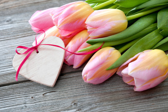 Colorful tulips and heart on wooden background