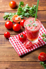 Gass of tomato smoothie, fresh tomatoes and cilantro on a dark wooden background . Vegetarian or healthy eating concept